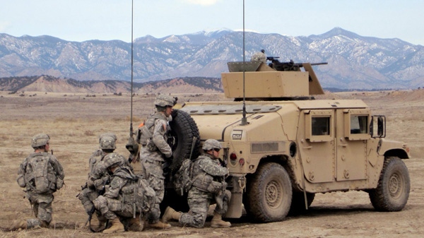 In this photo taken Tuesday, Feb. 28, 2010, soldiers take cover behind a Humvee as they approach a mock village at Fort Carson, Colo. They were participating in a live-fire exercise in preparation for deploying to Afghanistan. (AP Photo/Dan Elliott)