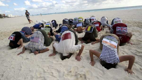 Sierra Club activists wearing flags, representing over 20 countries, take part in a protest by hiding their heads in the sand in the city of Cancun, Mexico Friday Dec. 3, 2010. (AP Photo)