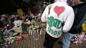 A Sandy Hook resident wears a handmade sweatshirt in support of his town while looking at a memorial to the Newtown shooting victims in the Sandy Hook village of Newtown, Conn., Saturday, Dec. 22, 2012.  (AP / Seth Wenig)