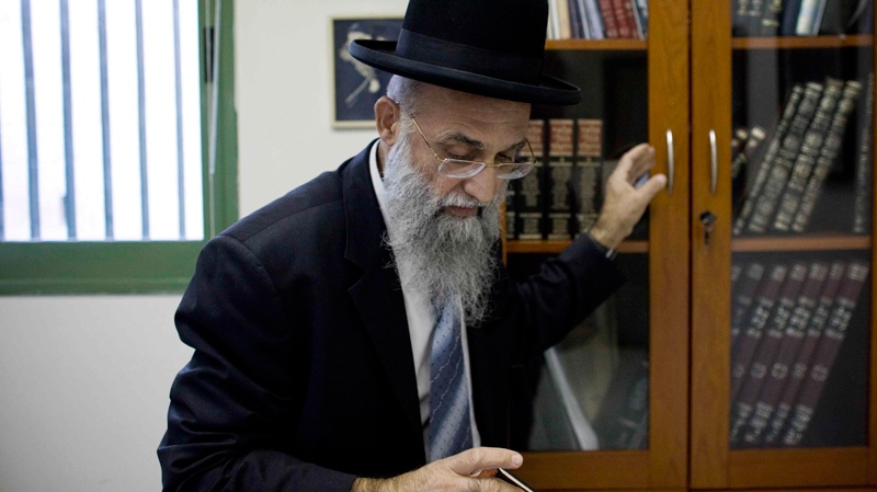 Israeli Rabbi Mordechai Nagari who recently signed a religious ruling barring Jews from selling or renting homes to non-Jews, takes a book from his cabinet in his office as he poses for a photo, in the Jewish West Bank settlement of Maaleh Adumim near Jerusalem, Tuesday, Dec. 7, 2010. (AP / Tara Todras-Whitehill)