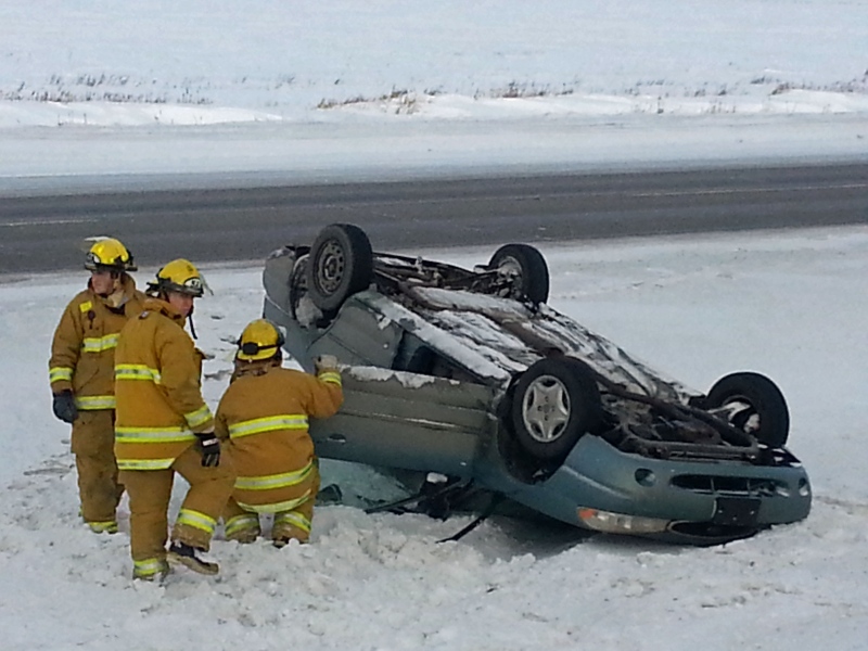 Firefighters attend to a car that rolled into the ditch Wednesday afternoon on Highway 1 near the Pilot Butte turnoff.