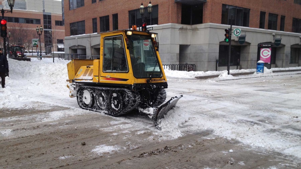 A small snowplow pushes snow in Montreal nearly a 
