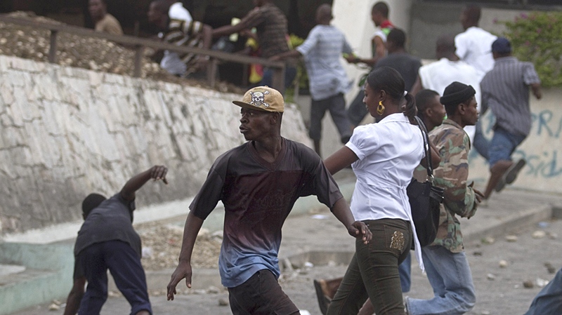 Protesters run away from U.N. peacekeepers during a protest as a woman walks by in Port-au-Prince, Haiti, Friday, Dec. 10, 2010. (AP / Guillermo Arias)