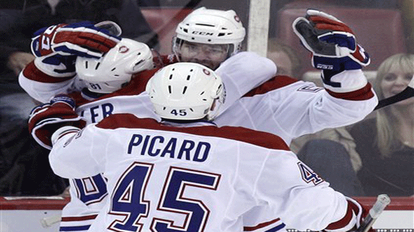 Montreal Canadiens left wing Benoit Pouliot, top, is congratulated by teammates Montreal Canadiens center Lars Eller and defenseman Alexandre Picard (45) after his goal during the third period of an NHL hockey game against the Detroit Red Wings in Detroit, Friday, Dec. 10, 2010. (AP Photo/Carlos Osorio)