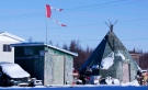 The remains of a Canadian flag can be seen flying over a building in Attawapiskat, Ont., on Nov. 29, 2011. (Adrian Wyld / THE CANADIAN PRESS)