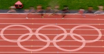 Runners make their way past a logo on the track during a women's 5000-metre heat at athletics in the Olympic Stadium at the 2012 Summer Olympics, London, Tuesday, Aug. 7, 2012. (Morry Gash / AP)