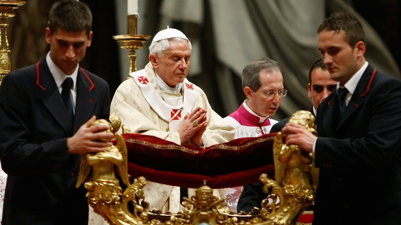 Two Vatican aids carry a kneeler as Pope Benedict XVI celebrates Christmas Mass in St. Peter's Basilica at the Vatican, Friday, Dec. 24, 2010. (AP / Andrew Medichini)