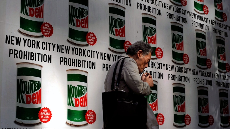 A man lights a cigarette as he walks past an advertisement created in collaboration with Mountain Dew and New York Art Department, Thursday, Sept. 13, 2012, on 13th Street in New York.  (AP Photo / Jeffrey Furticella)