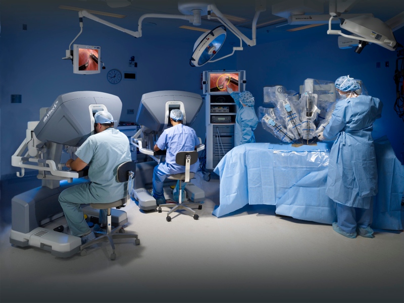 A horizontal action shot shows an operating room featuring the da Vinci Si Surgical System. (Courtesy Intuitive Surgical Inc.)