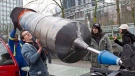 Engineer and artist Hugh Patterson and his team lift a giant syringe into place for his art project titled "Quick Fix" outside a hotel in downtown Vancouver, where the hearings for the Enbridge Northern Gateway pipeline are taking place, February 1, 2013. (Richard Lam/ THE CANADIAN PRESS)