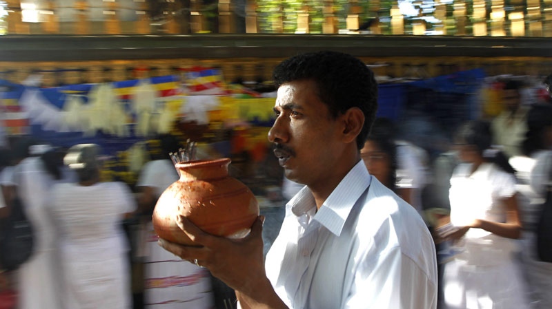 Sri Lankan Buddhist devotees pray at a temple as a man, front, carries his offering of water and incense to mark the first day of the new year in Colombo, Sri Lanka, Saturday, Jan. 1, 2011. (AP Photo/ Eranga Jayawardena)