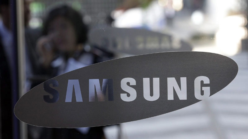 A woman uses her mobile phone near the logo of Samsung Electronics Co. at its headquarters in Seoul, South Korea, Friday, Oct. 29, 2010. (AP Photo/ Lee Jin-man)