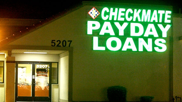 Neon signs illuminate a payday loan business in Phoenix on Tuesday, April 6, 2010. (AP / Ross D. Franklin)