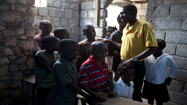 Thony Jean-Baptiste chats with students in his school amid the quake-battered ruins of his Haitian neighbourhood Friday, December 10, 2010 in Port-au-Prince. L'Ecole de l'Espoir (or School of Hope) is a modest symbol of progress as Haiti struggles to pull itself to its feet one year after the disaster. THE CANADIAN PRESS/Paul Chiasson