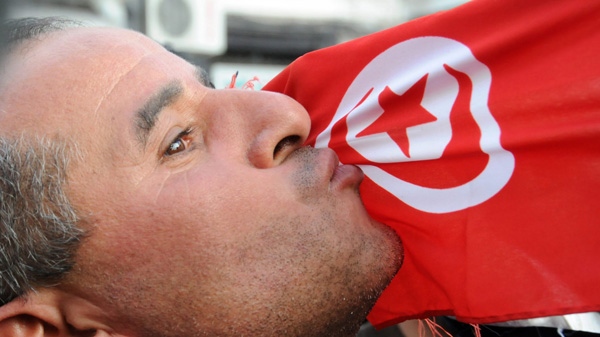 A man kisses the Tunisian flag during a demonstration in Tunis, Tunisia, against high prices and unemployment, Saturday Jan. 8, 2011. (AP Photo/Hassene Dridi)