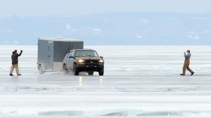 A fisherman guides a vehicle crossing over a crack as another one captures the scene with his cellular phone Monday afternoon, Jan. 3, 2011 on Lake Winnebago at the foot of Waugoo Avenue in Oshkosh, Wis. (AP Photo/The Oshkosh Northwestern, Shu-Ling Zhou)
