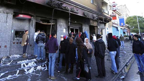 Residents gather outside a vandalized bank in Ettadhamoun, west of Tunis, Wednesday Jan. 12, 2011. Riots were reported late Tuesday in the Ettadhamoun neighborhood five kilometres from Tunis.