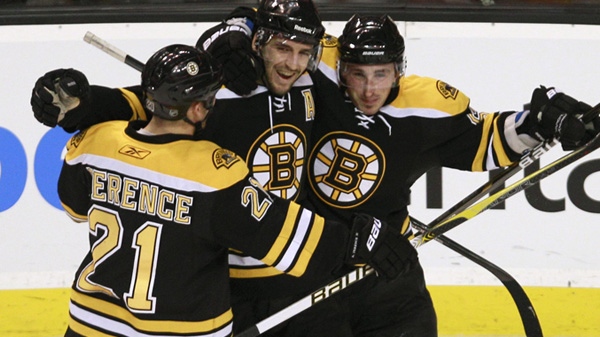 Boston Bruins center Patrice Bergeron, center, is congratulated by teammates Andrew Ference, left, and Brad Marchand, right, after scoring the third goal of his hat trick against the Ottawa Senators, during the third period of an NHL hockey game in Boston, Tuesday, Jan. 11, 2011. (AP Photo/Charles Krupa)