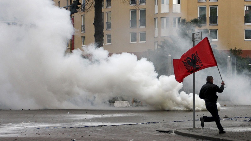 An opposition supporter runs with the Albanian national flag after clashes with police during a protest in Tirana, Albania, Friday, Jan. 21, 2011. (AP Photo/Visar Kryeziu)