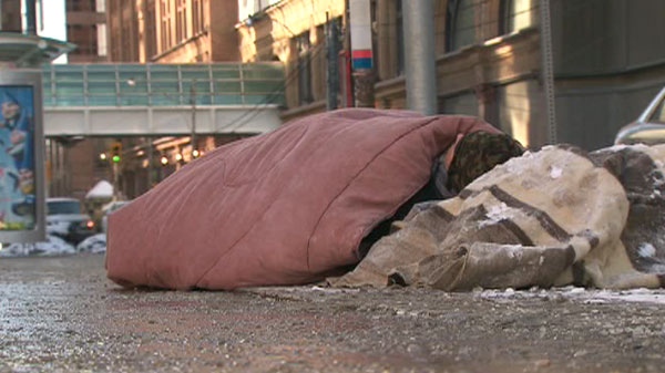 A homeless man seeks warmth under blankets on a Toronto sidewalk during a cold snap Sunday, Jan. 23, 2011.