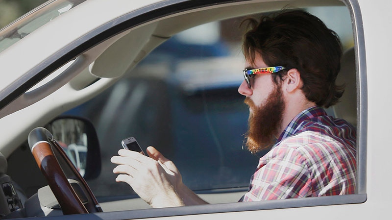 A man looks at his phone as he drives through traffic in Dallas, on Tuesday, Feb. 26, 2013. (AP / LM Otero)