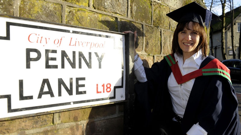 In this image made available by Liverpool Hope University, Wednesday Jan. 26, 2011, former Miss Canada finalist Mary-Lu Zahalan-Kennedy poses next to the Penny Lane street sign in Liverpool, England, after becoming the first person in the world to graduate with a Masters degree in The Beatles. (Alan Edwards / Liverpool Hope University) 