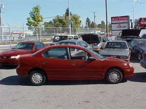 The suspect vehichle is a dark red or maroon coloured sedan, similar in make to an older model Dodge Neon.