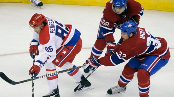 Washington Capitals center Mathieu Perreault (85) works the puck past Montreal Canadiens left wing Travis Moen (32) and defenseman Yannick Weber (68) during the first period of their NHL hockey game at the Verizon Center in Washington, Tuesday, Feb. 1, 2011. (AP Photo/Susan Walsh)