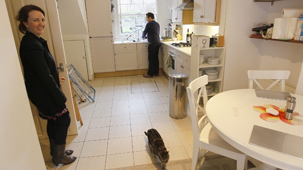 Ed and Joanna Thornton and one of their cats seen inside their house near King's Cross in London, Friday, Jan., 28, 2011. (AP Photo/Alastair Grant)