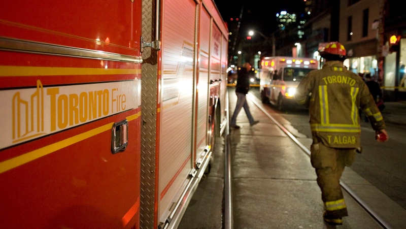 A Toronto Firefighter walks past a fire truck in Toronto on Thursday night, April 21, 2011. (Aaron Vincent Elkaim / THE CANADIAN PRESS)