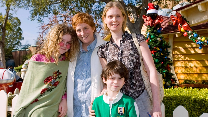 In this image released by Disneyland, actress Cynthia Nixon, right, poses with her daughter Samantha, 12, left, her partner Christine Marinoni and son Charlie, 6, foreground, outside Mickey Mouse's home in Toontown during a visit to Disneyland in Anaheim, Calif., Wednesday, Dec. 31, 2008.