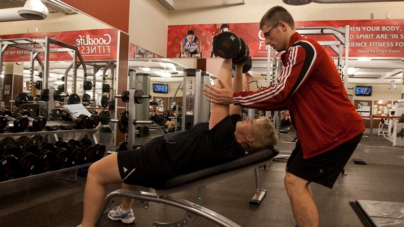 Trainer Tim Martin spots Paula Moors as she works on her incline dumbbell press, part of her personalized training plan at the GoodLife Fitness club in Dartmouth, N.S. on Friday, Dec. 30, 2011. (THE CANADIAN PRESS / Andrew Vaughan)