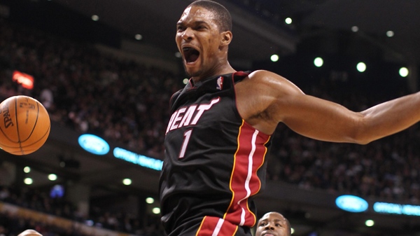 Miami Heat forward Chris Bosh lets out a yell after slamming home a dunk against Toronto Raptors guard Leandro Barbosa (20) and Ed Davis (32) during first half NBA action in Toronto on Wednesday, Feb. 16, 2011. (Frank Gunn / THE CANADIAN PRESS)  