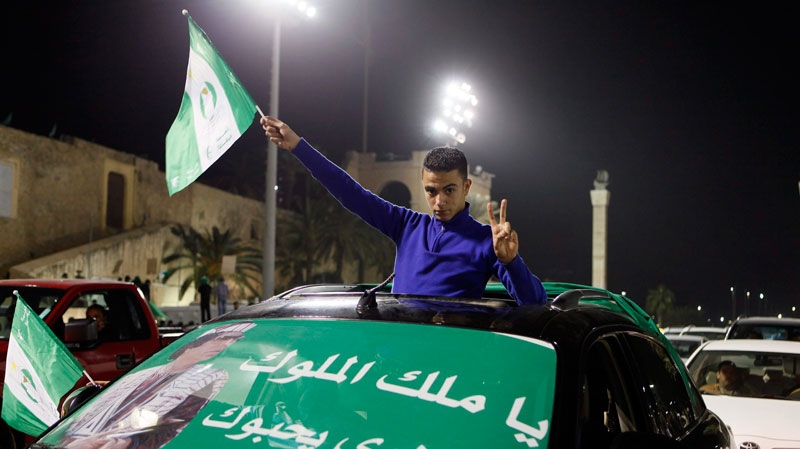 A supporter of Libyan President Moammar Gadhafi posses for the camera while holding a flag during a pro-government demonstration in Tripoli early Thursday Feb. 17, 2011. (AP / Abdel Meguid al-Fergany)