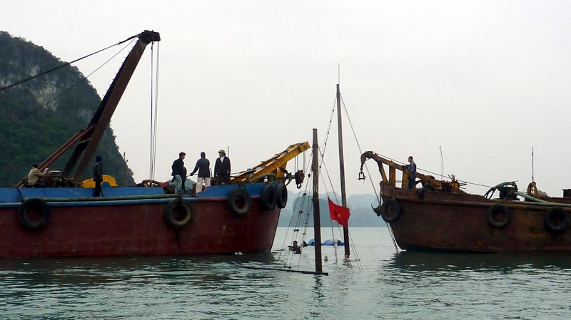 Vietnamese workers try to hoist the sunken vessel, partially seen at center, out of the water at the famed Ha Long Bay in northern Quang Ninh province, Vietnam Friday Feb. 18, ,2011, a day after 11 vacationers from the U.S., Britain, Australia, Japan, Russia, France, Sweden and Switzerland died along with their Vietnamese tour guide in the country's deadliest tour boat accident since opening up to foreign visitors 25 years ago. (AP / Dinh Tran Trung Hau)