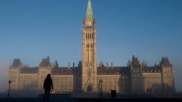Sun illuminates the Peace Tower as a visitor makes their way onto Parliament Hill in Ottawa, Nov. 3, 2010. (Adrian Wyld / THE CANADIAN PRESS)