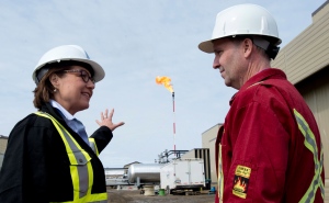 Natural gas is burned off in the background as Liberal leader Christy Clark speaks with local candidate Mike Bernier at the Encana compressor site in Dawson Creek, B.C. Thursday, April 18, 2013. THE CANADIAN PRESS/Jonathan Hayward
