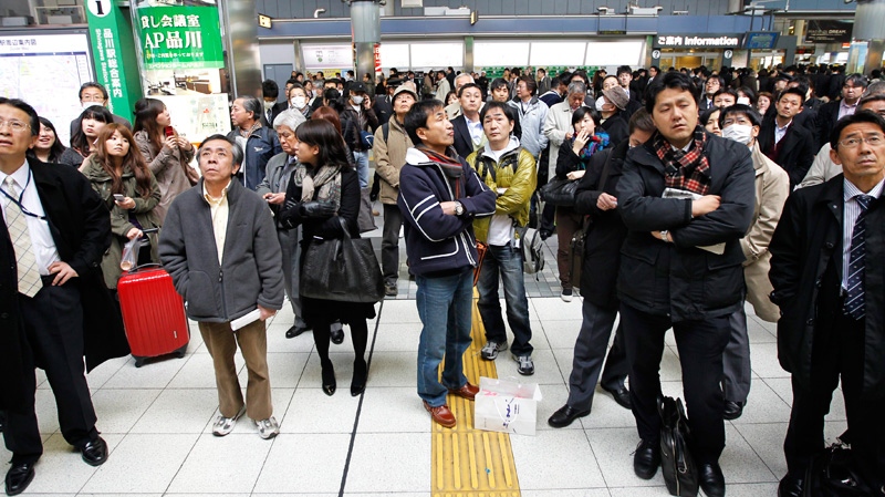 Train passengers wait at Tokyo's Shinagawa station to get first-hand information on train service which was halted following a very strong earthquake on Friday, March 11, 2011. (AP / Hiro Komae)