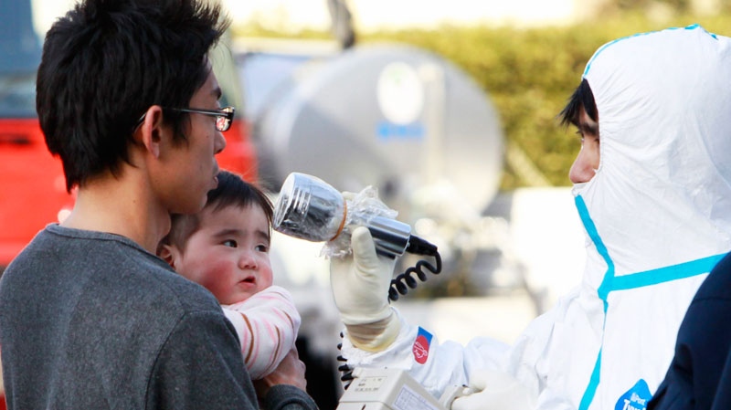 A man holds his baby as they are scanned for levels of radiation in Koriyama, Fukushima Prefecture, Japan, Sunday, March 13, 2011.  (AP / Mark Baker)