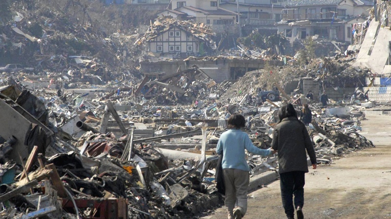 A couple walk along the rubble at a residential area in Onagawa, Miyagi Prefecture, northern Japan, Sunday, March 13, 2011. (AP / The Yumiuri Shimbun)
