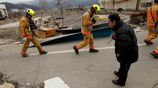 Members of a Fairfax County, Va, search and rescue team from the U.S. bow their heads in response as they are greeted by a local man as they walk through a damaged area whilst searching for tsunami survivors in Ofunato, Japan, Tuesday, March 15, 2011. (AP / Matt Dunham)