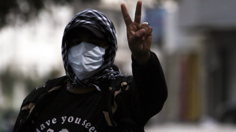 An anti-government protester wearing a mask to protect against tear gas gestures during clashes with riot police in the Shiite Muslim village of Jidhafs, Bahrain, on the outskirts of the capital of Manama on Thursday, March 17, 2011. (AP / Hasan Jamali)