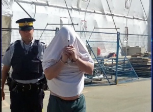Gavin Waffle hides his face as he is escorted from Court of Queen's Bench in Regina on Wednesday.