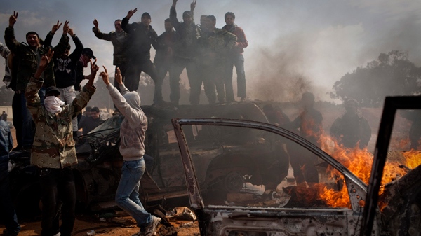 Libyan rebels celebrate next to burning cars after Libyan leader Moammar Gadhafi's forces where pushed back from Benghazi, eastern Libya, Saturday, March 19, 2011. (AP / Anja Niedringhaus)