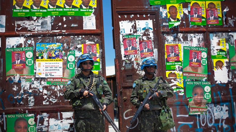 UN peacekeepers from Brazil stand guard at the gate of a polling station ahead of the second round of elections in Cite Soleil, Port-au-Prince, Haiti, Saturday March 19, 2011.(AP / Ramon Espinosa)