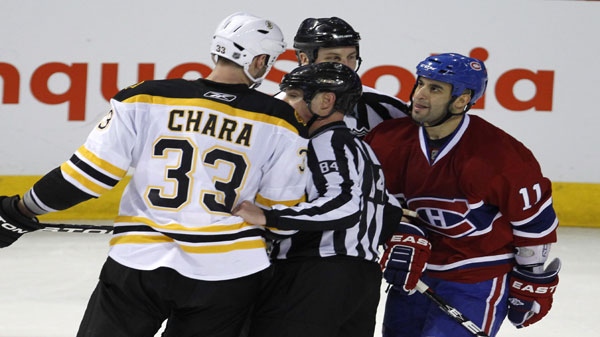 Referees keeps Montreal Canadiens' Scott Gomez away from Boston Bruins' Zdeno Chara after hitting Canadiens' Max Pacioretty during second period NHL hockey action Tuesday, March 8, 2011 in Montreal. THE CANADIAN PRESS/Paul Chiasson