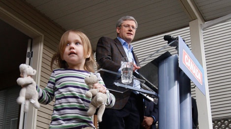 Prime Minister Stephen Harper speaks as two-and-a-half-year-old Fiona Wellburn plays with her toys during a campaign stop at the Wellburn family home in Saanich, B.C., Monday, March 28, 2011. THE CANADIAN PRESS/Adrian Wyld