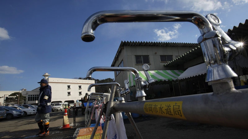 A worker from a water supply department walks by water faucets set up for survivors at a shelter in the devastated town of Yamamoto, Miyagi Prefecture, northeastern Japan, Monday, March 28, 2011. The March 11 quake off Japan's northeast coast triggered a tsunami that barreled onshore and disabled the Fukushima nuclear complex. (AP Photo/Vincent Yu)