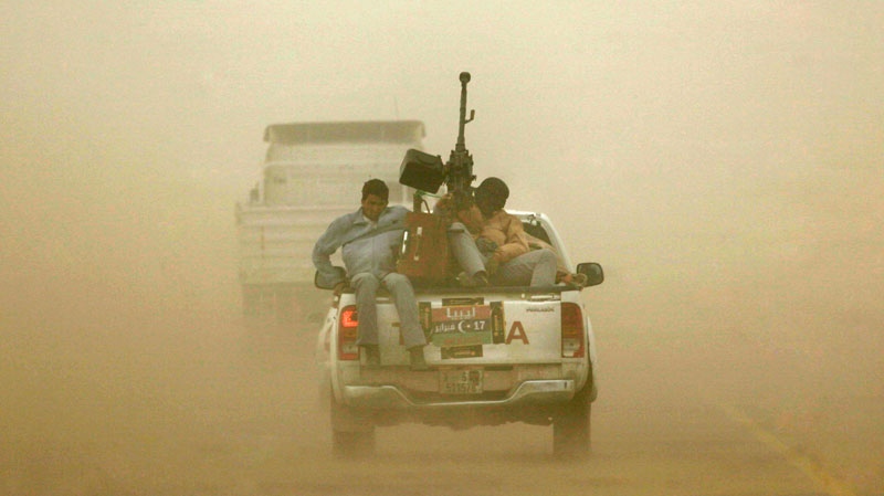 Libyan rebels riding at the back of an armed pickup truck brave a sand storm at the main road heading to Benghazi while leaving the eastern town of Ajdabiya, Libya, Wednesday, March 30, 2011. (AP / Nasser Nasser)