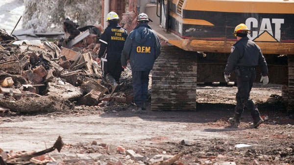 Investigators examine the rubble of an apartment building in Woodstock Ontario, Wednesday, March 30, 2011. (Geoff Robins / THE CANADIAN PRESS) 